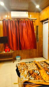 1 dormitorio con cama y cortina roja en altafs motel, en Matheran