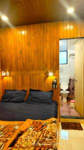 1 dormitorio con pared de madera, cama y aseo en altafs motel, en Matheran