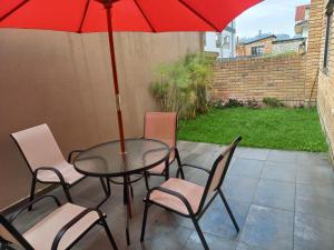 einen Tisch und Stühle mit einem roten Regenschirm auf einer Terrasse in der Unterkunft Departamento excelente ubicación con parqueo in Cuenca