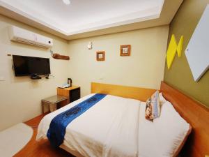 a bedroom with a bed and a flat screen tv at Kenting Waterfront Hotel in Kenting