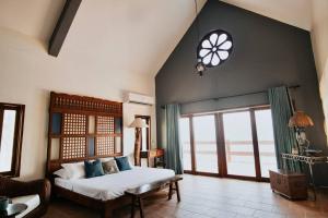 um quarto com uma cama e uma grande janela em Exclusive Beachfront House w/ Pool & Saltwater Tub em Catmon