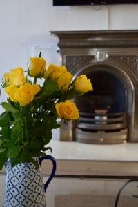 オーバンにあるFlat in Oban Town Centreの黄色いバラをストーブの前に置いた花瓶