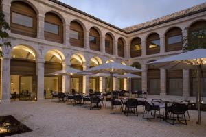 um pátio exterior com mesas, cadeiras e guarda-sóis em Parador de Alcalá de Henares em Alcalá de Henares