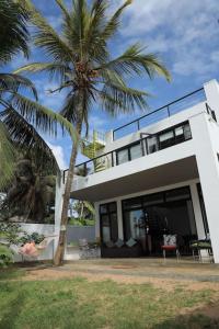 une maison blanche avec un palmier devant dans l'établissement Yachtmans House, à Matara