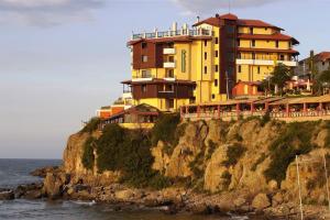 een geel gebouw op een klif naast de oceaan bij Hotel Parnasse in Sozopol