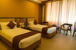 una habitación de hotel con 2 camas y una silla en Hotel Harisree Kollam, en Kollam