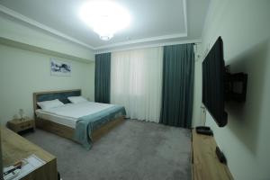 a bedroom with a bed and a flat screen tv at HOTEL NAVRUZ in Urganch