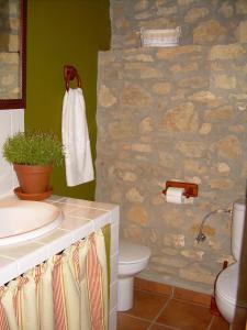 a bathroom with a toilet and a stone wall at Casa Rural el Castellet in La Jana