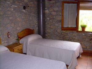 sypialnia z 2 łóżkami i kamienną ścianą w obiekcie Casa Rural el Castellet w mieście La Jana