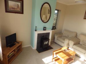 a living room with a fireplace and a mirror at Crow Corner in Yoxford