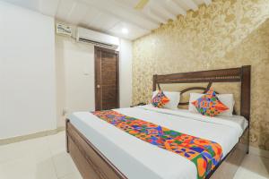 a bedroom with a large bed with colorful sheets and pillows at FabHotel The Villa in Kānpur