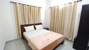 um quarto com uma cama e uma janela com cortinas em Eve's appartment em Meppādi