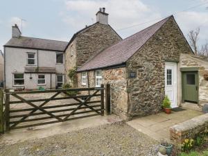 a stone cottage with a wooden gate in front of it at Ty Gwenyn in Holyhead
