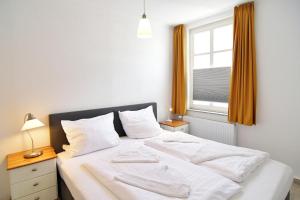 a bedroom with a bed with white sheets and a window at Hamburg-App-06 in Ahlbeck