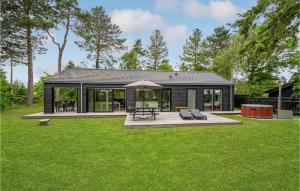 a small black house with a patio and grass at Beautiful Home In Idestrup With Kitchen in Marielyst