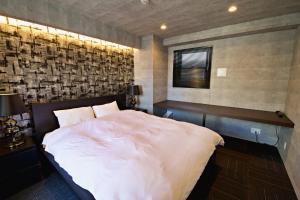 a bedroom with a white bed and a brick wall at Regalo shibaura 801 in Tokyo