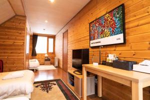 ニセコ町にあるNiseko HyKrots IKIGAI Villageの木製の壁のベッドルーム(壁にテレビ付)