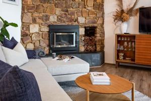 a living room with a stone wall with a fireplace at The Lookout, Eagle Bay in Dunsborough