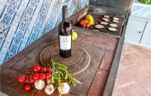 una botella de vino en una mesa con frutas y hortalizas en Cozy Home In San Michele Di Ganzari With Kitchen, en San Michele di Ganzaria