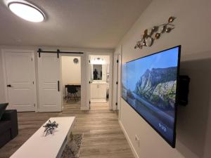 uma sala de estar com uma grande televisão de ecrã plano na parede em Cozy New Suite in NW Calgary em Calgary