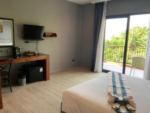 Habitación de hotel con cama, escritorio y balcón. en Aonang Inn en Krabi