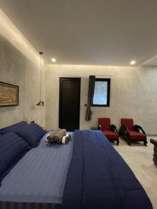 a bedroom with a large blue bed with two red chairs at DJipangan Home in Bantul