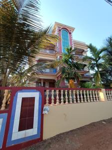 une maison avec une clôture et des palmiers devant elle dans l'établissement Pappa's Guest House, à Arambol