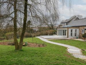 a house with a tree and a walkway at Moohey Barn in Liskeard