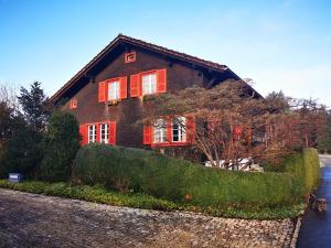 una casa con ventanas con persianas rojas y algunos arbustos en Marmottin en Lucerna