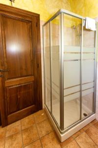 a glass shower stall next to a wooden door at Country House Le Calvie in Camerino