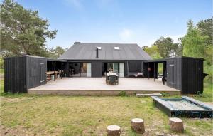 a black house with a deck in a field at 5 Bedroom Awesome Home In Ebeltoft in Ebeltoft
