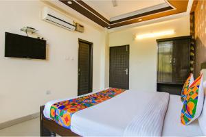 a bedroom with a bed and a flat screen tv at FabHotel City Palace in Dehradun