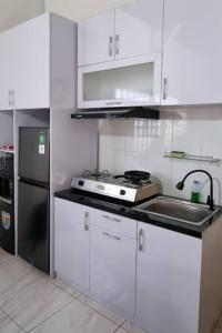 a kitchen with white cabinets and a sink and a refrigerator at Betuah Say [2BR City Center Holiday Home] in Tanjungkarang