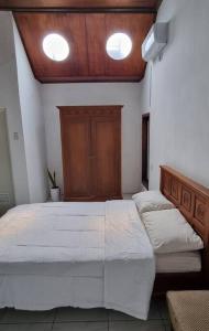 1 dormitorio con 2 camas blancas y cabecero de madera en Betuah Say [2BR City Center Holiday Home] en Tanjungkarang