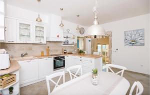 a kitchen with white cabinets and a table and chairs at Stunning Home In Brsecine With Outdoor Swimming Pool in Brsečine