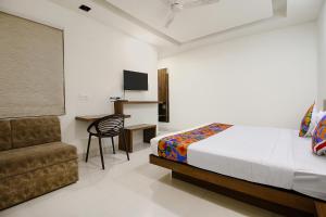a bedroom with a bed and a chair and a desk at FabExpress Comfort Stay I in Bhopal