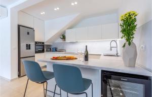 a kitchen with white cabinets and blue chairs at Nice Home In Zrnovnica With Heated Swimming Pool in Žrnovnica