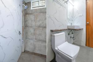 a white bathroom with a toilet and a shower at FabExpress Comfort Stay I in Bhopal