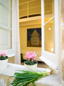 Casa di Lo Suites في ليتشي: مزهريتين بيض مع زهور وردية على حافة النافذة