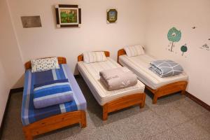 Cette chambre comprend 3 lits et une chaise. dans l'établissement Carlos Backpacker, à Minxiong