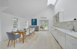 - une cuisine blanche avec une table et des chaises en bois dans l'établissement Amazing Home In Rdvig Stevns With Kitchen, à Rødvig