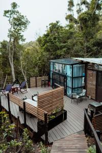 une terrasse en bois avec une maison en verre. dans l'établissement The Stargazing Cube - Misty Mountain Reserve, à Stormsrivier