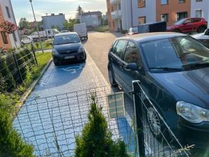 two cars parked in a parking lot next to a fence at Apartament z ogródkiem in Piła