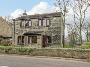 a stone house on the side of the road at Butts Cottage in Farnley Tyas