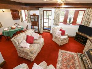 sala de estar con sillas, mesa y TV en Butts Cottage en Farnley Tyas