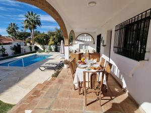 a patio with a table and chairs next to a pool at Villa Las Niñas Costa del Sol in Mijas