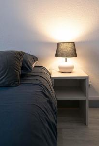 a bed with a lamp on a night stand next to it at Le Venise - appartement design - centre ville - parcs in Vichy