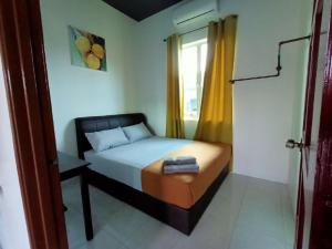 a small bedroom with a bed and a window at Aja Retreat Chalet in Jitra