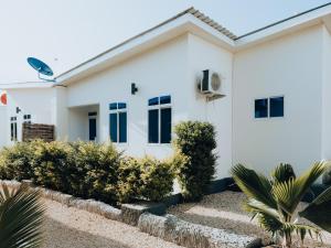 een wit huis met blauwe ramen en struiken bij BT Private Villas with Swimming Pool in Mkunguni