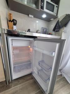 an empty refrigerator with its door open in a kitchen at Studio 1 à La Trinité proche de Nice, Monaco et l'Italie in La Trinité